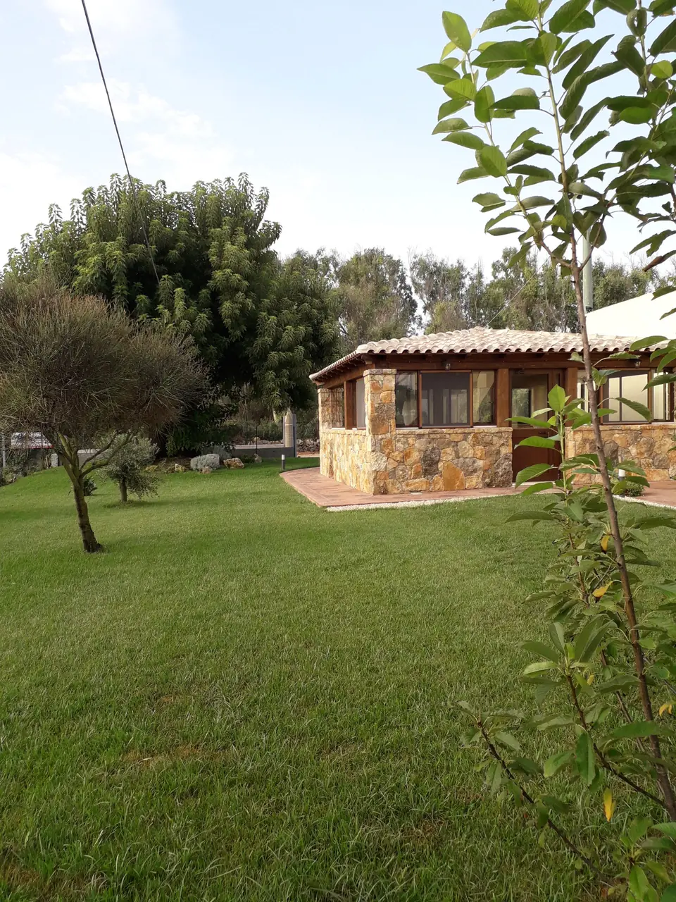 Prato verde e alberi attorno alla casetta in pietra dell’agriturismo